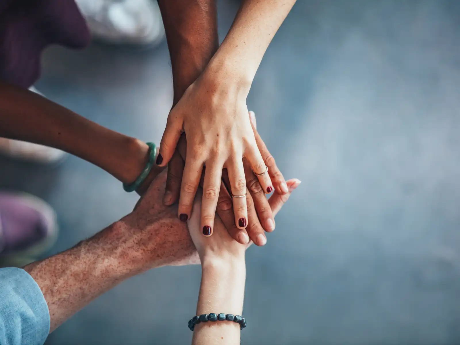 Close-up of diverse hands stacked together in unity, symbolizing teamwork, support, and connection in ADHD couples group therapy.