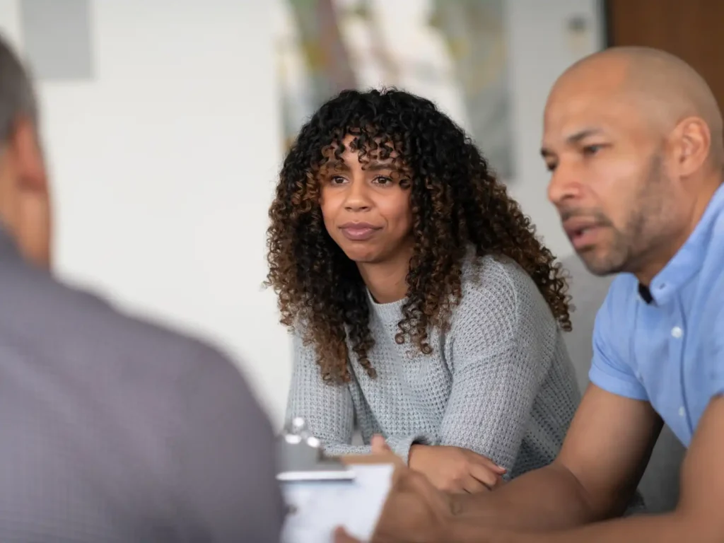 A couple sits in a therapy session with a professional, engaging in open and honest discussion, representing the supportive guidance offered by couples therapists in LA.