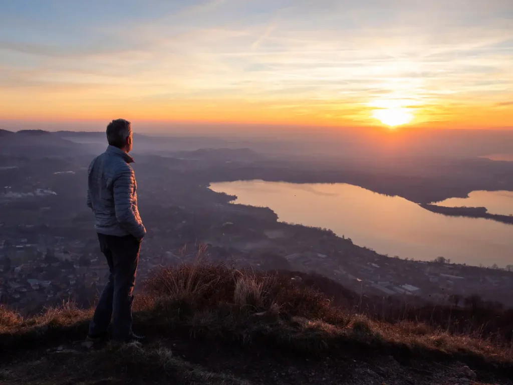 A man stands atop a hill, gazing at the sunrise over a peaceful landscape, symbolizing reflection, healing, and personal growth through individual therapy in Los Angeles.