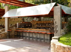 The bar area at Verana, Mexico, an open air setting with rustic stone touches and bar stools. The perfect place for couples to unwind during their retreat.