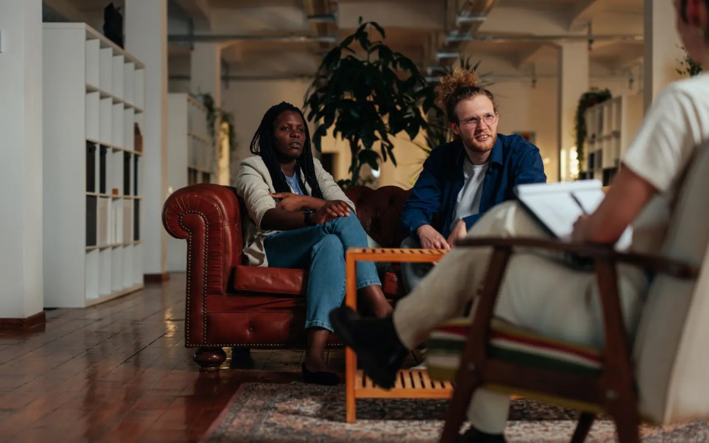 An interracial couple in a couple's therapy session sitting on a leather couch
