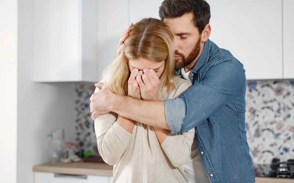 A man comforting a grieving woman, demonstrating the impact of grief on relationship dynamics