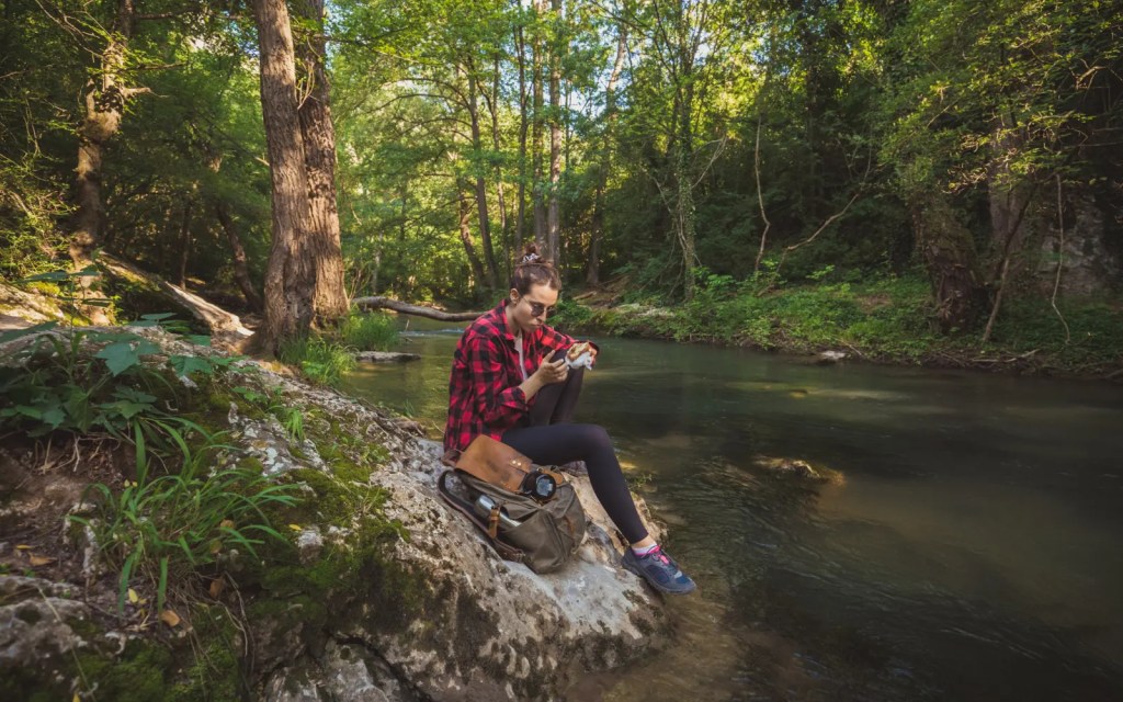 A woman taking a break by a lake having a stress-free hike because of the reduced stress she feels after a couple therapy