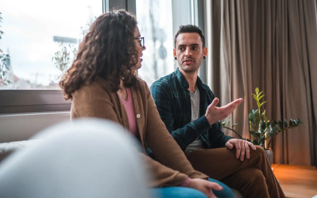 A Latino looking man and woman in couple's therapy sitting on a couch in a therapists office