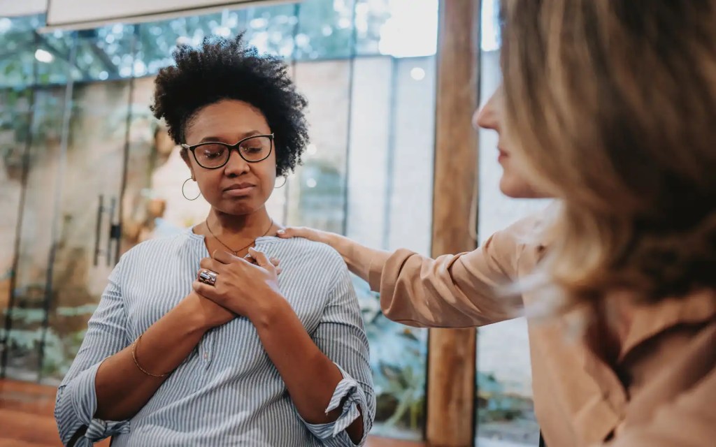 A black woman holding her hands over her heart in an affirming pose, representing the emotional safety EFT gives couples