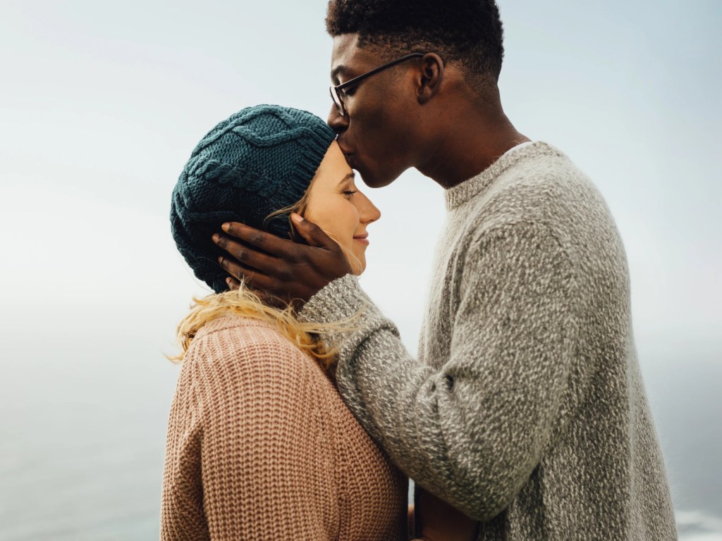 A black man tenderly kissing the forehead of his white soon to be wife, representing premarital counseling in Los Angeles