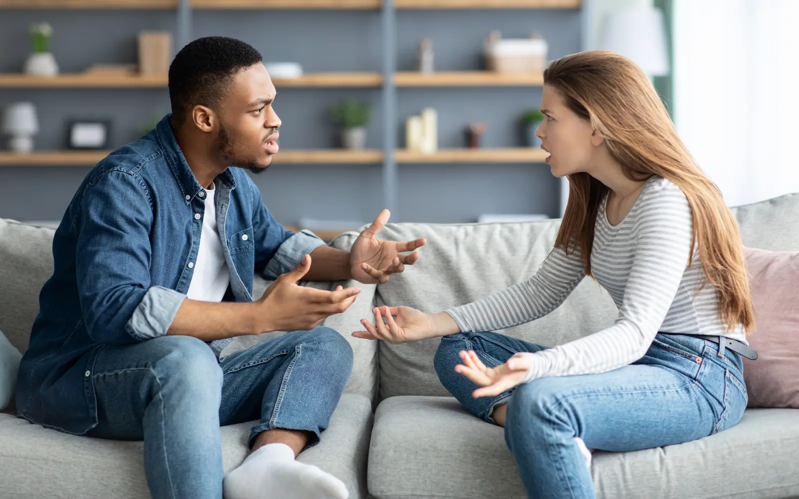 A black man and white woman arguing on a sofa, representing the kinds of situations many interracial couples find themselves in before seeking therapy