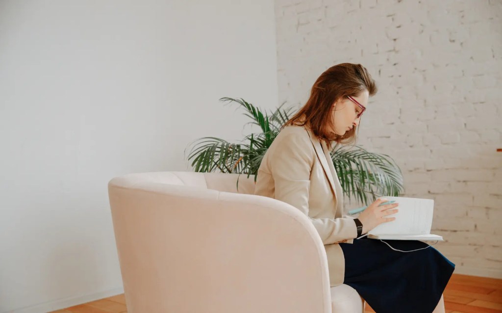 A therapist sitting in a chair, reviewing her notes during her training for her couples therapy qualification