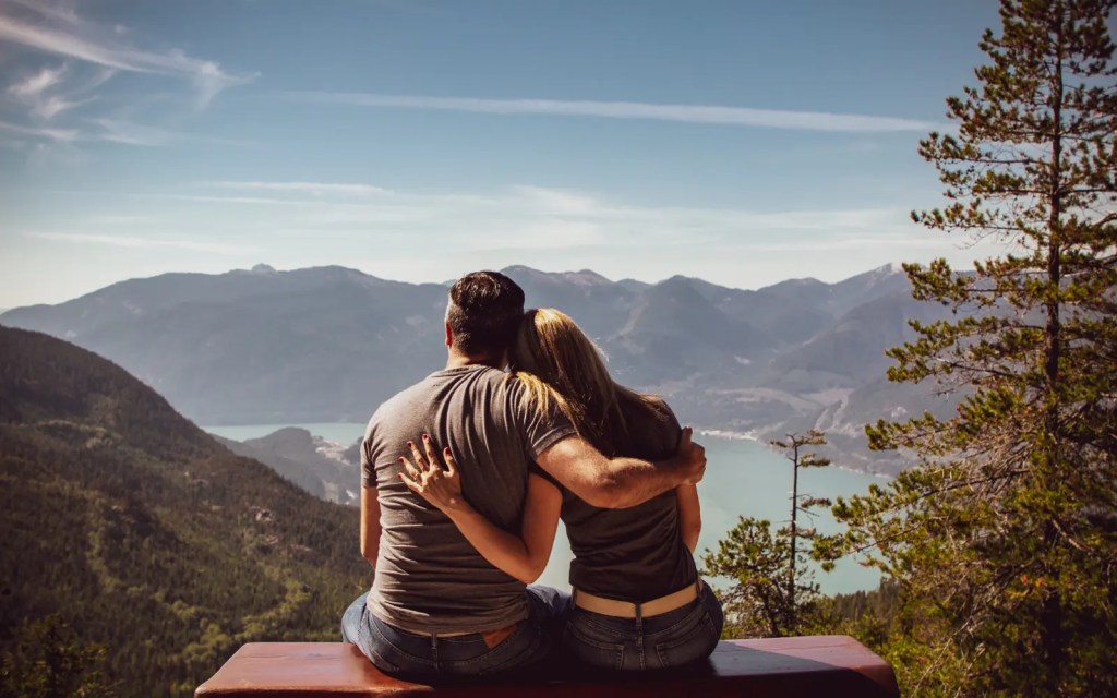 A couple embracing while viewing a stunning mountain scene, representing connection through couples therapy
