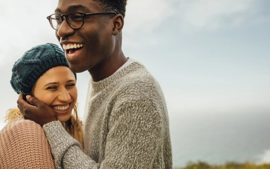 An interracial couple smiling and laughing outdoors, representing the impact of EFT for couples in Los Angeles