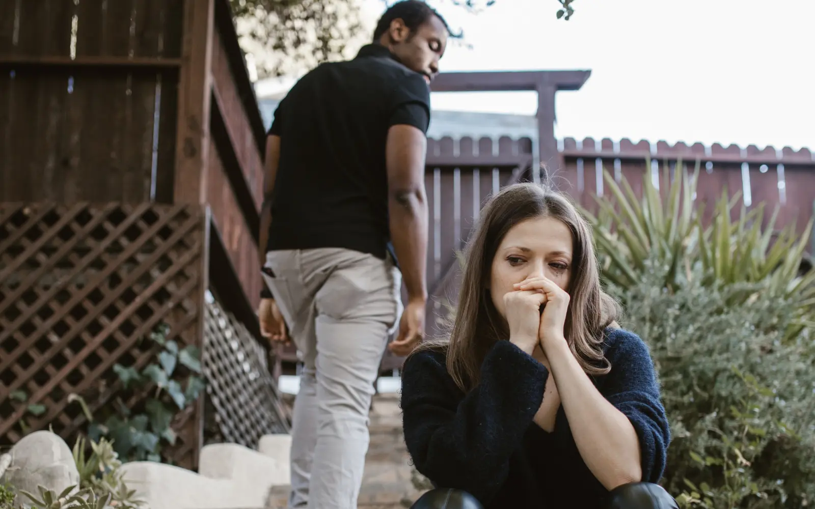 A man walking away from a nervous and scared looking woman, representing the lack of safety often present in narcissistic couples