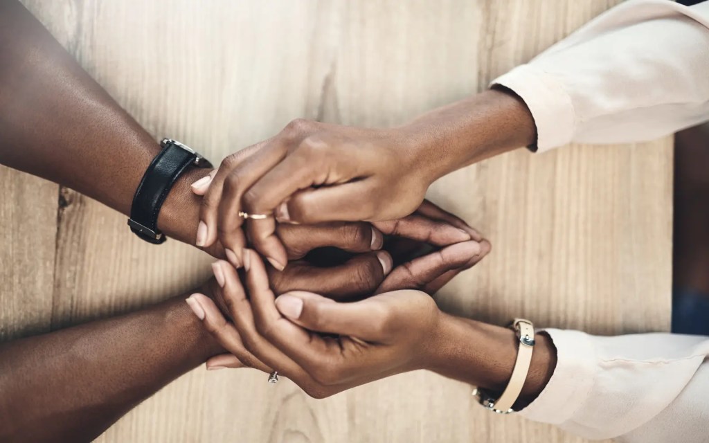 A woman and man holding hands across a table, representing safety in relationships through couples therapy
