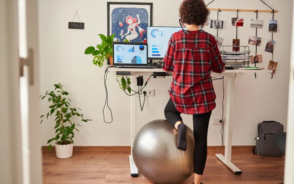 Workplace-adjustments-after-neuropsychological-assessment A woman kneeling on a yoga ball and working at a standing desk, representing how neuropsychological testing can unlock access to workplace adjustments to help you succeed