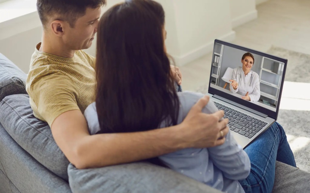 A couple sitting on a sofa with a laptop during an online couples therapy session with one of GGPA's Los Angeles therapists