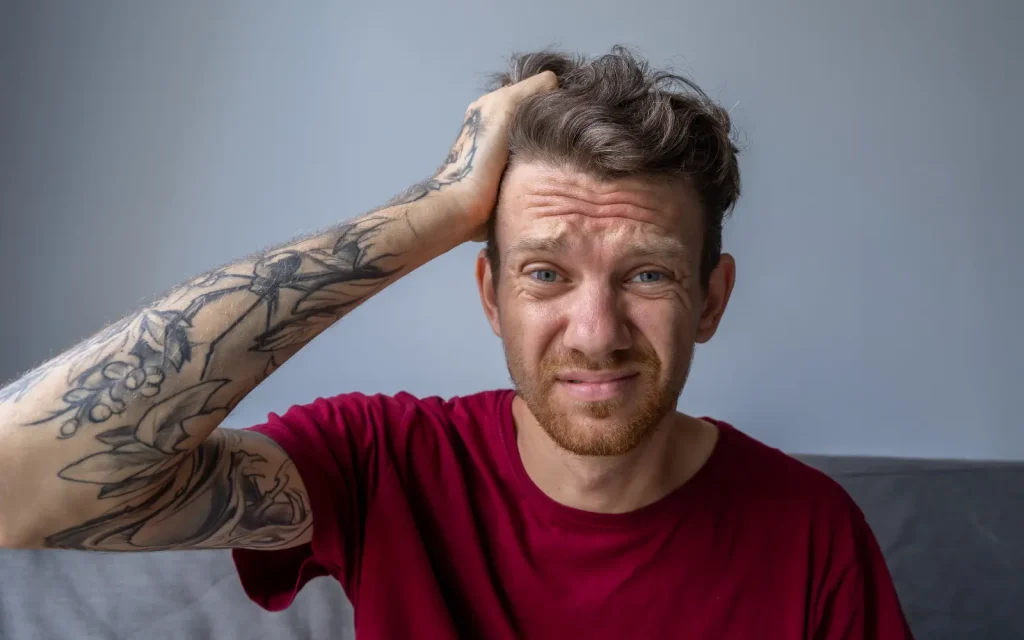 A man scratching his head in confusion, representing the question "Will my therapist understand my adult ADHD?"