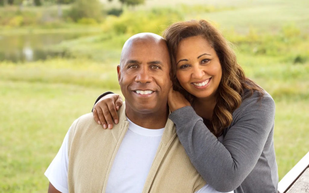 An interracial couple smiling at the camera, representing cultural differences in couples therapy.