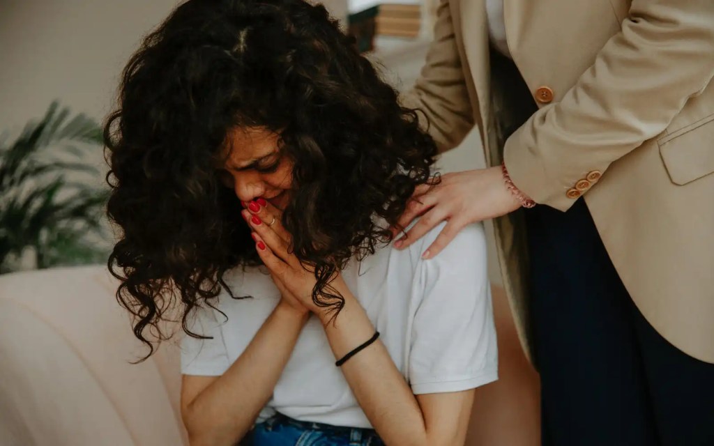 A woman crying and being comforted in a grief counseling session in Los Angeles