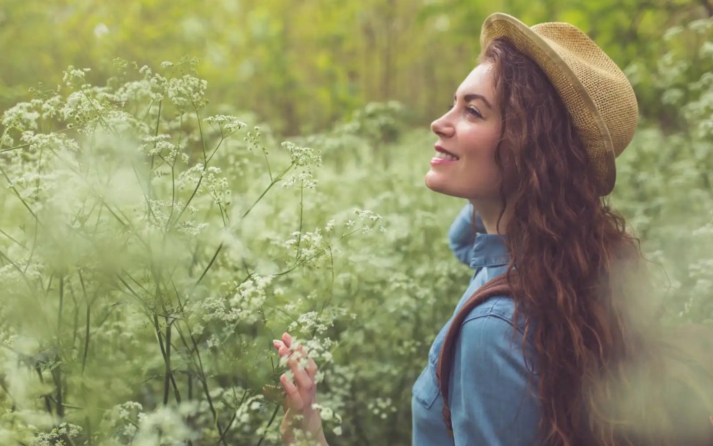 A woman smiling and walking through nature, representing the positive impact of reconnecting with yourself after trauma therapy