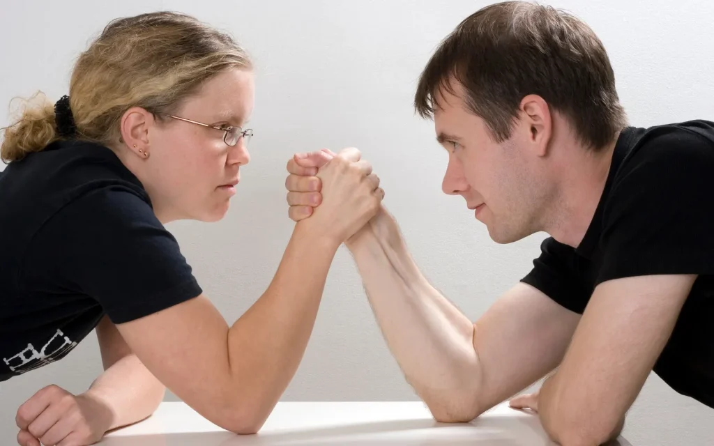 A man and woman arm wrestling, representing the question which gender goes to therapy more?