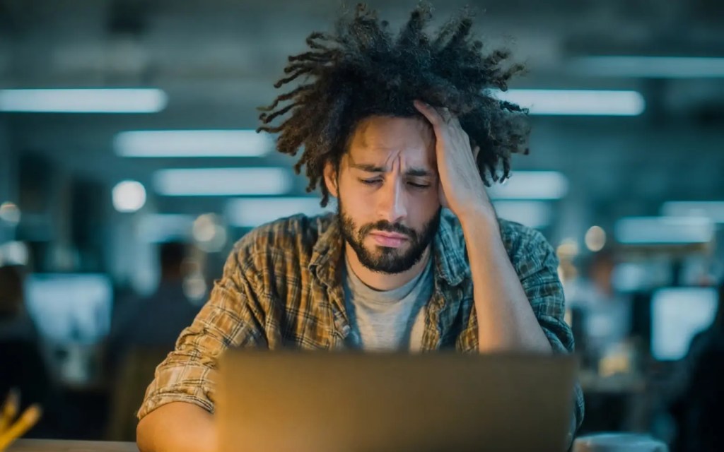 A man with his head in his hands, representing autistic burnout