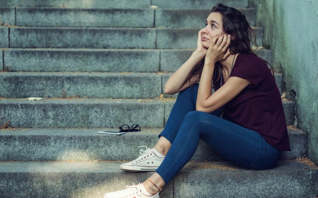 A woman sitting on outdoor steps alone, representing the loneliness often present in ADHD relationships
