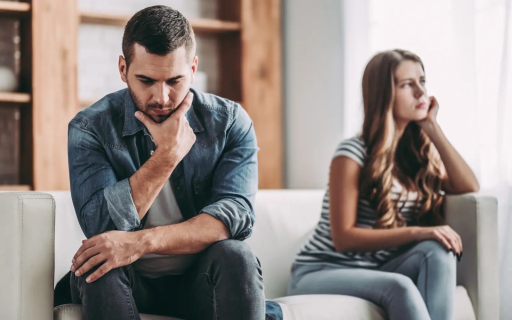 A couple after a fight sitting on opposite sides of a couch, representing the need for ADHD couples counseling