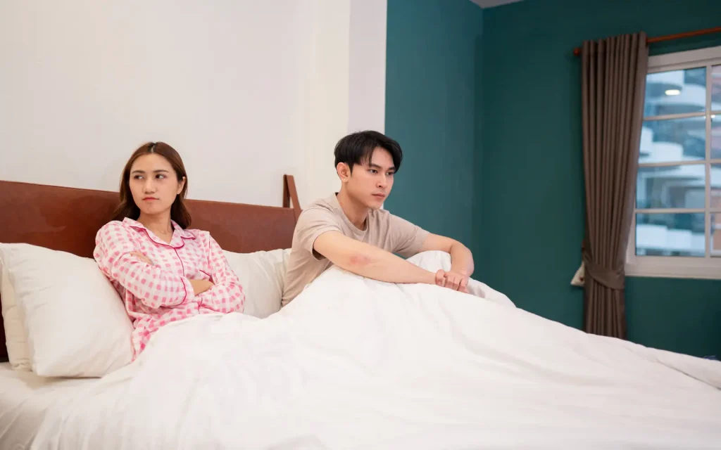 A couple facing away from each other in bed, representing the question: Why do people with ADHD struggle with relationships?