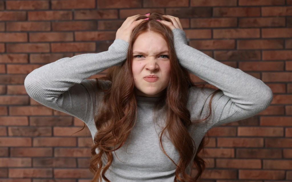 A woman with her head in her hands, representing emotional burnout in ADHD relationships